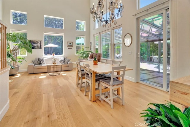 interior space featuring a notable chandelier, baseboards, a high ceiling, and light wood-style flooring