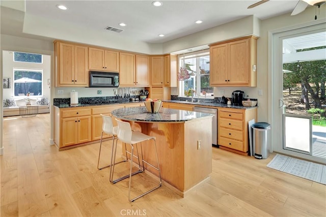 kitchen with light wood-style floors, light brown cabinets, visible vents, and black microwave