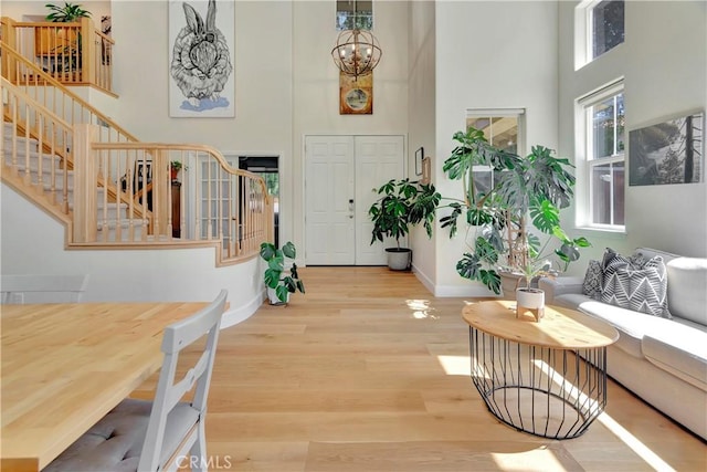 entryway with wood finished floors, stairway, a chandelier, baseboards, and a towering ceiling