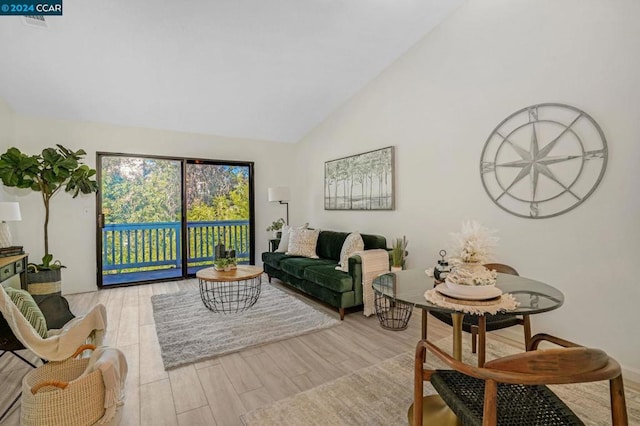 living room with light wood-type flooring and high vaulted ceiling