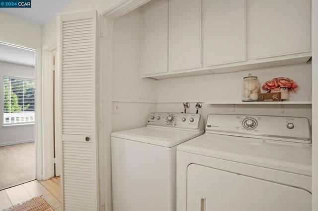 clothes washing area featuring cabinets, independent washer and dryer, and light wood-type flooring