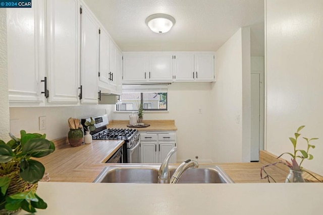 kitchen with gas range, sink, and white cabinets