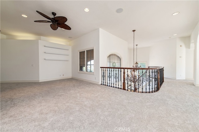 carpeted empty room featuring ceiling fan with notable chandelier