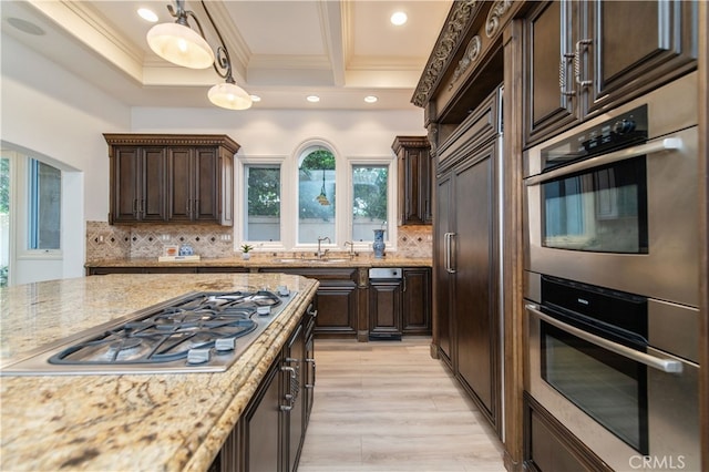 kitchen with pendant lighting, light stone counters, backsplash, appliances with stainless steel finishes, and dark brown cabinetry