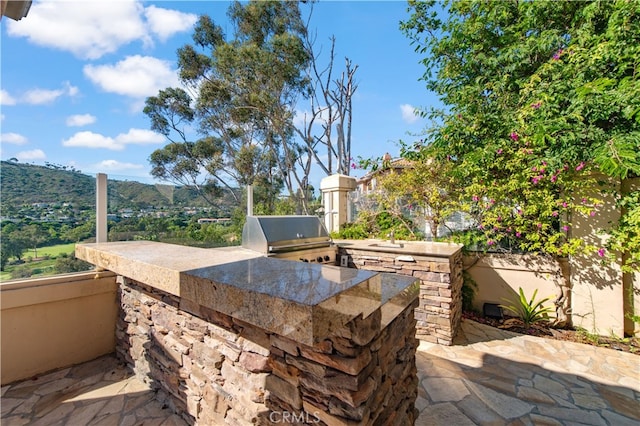 view of patio / terrace with a mountain view, area for grilling, and an outdoor kitchen