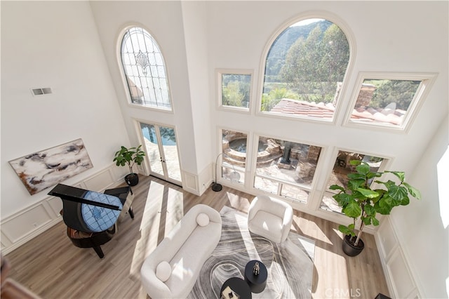 living room featuring a high ceiling, light hardwood / wood-style floors, and a wealth of natural light