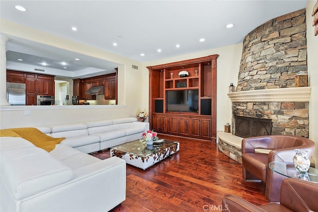 living room featuring a stone fireplace and dark hardwood / wood-style flooring