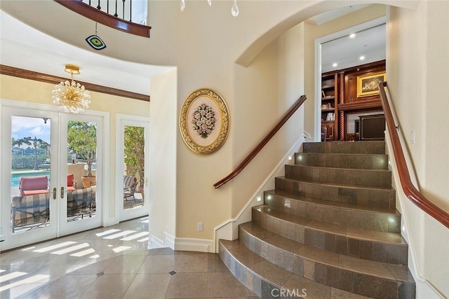 entrance foyer featuring french doors, ornamental molding, a chandelier, and tile patterned flooring