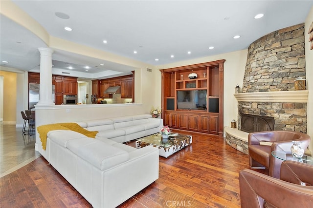 living room with ornate columns, a fireplace, and dark hardwood / wood-style flooring