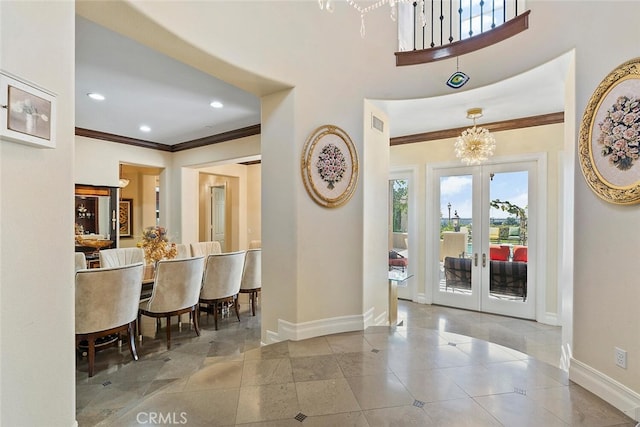 entrance foyer featuring a notable chandelier, ornamental molding, and french doors