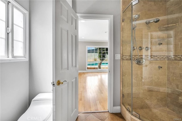 bathroom with ornamental molding, toilet, a shower with door, and hardwood / wood-style floors