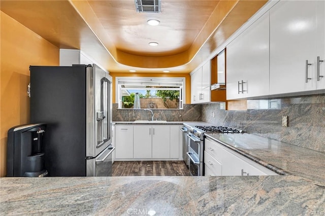 kitchen with light stone counters, white cabinets, sink, dark wood-type flooring, and stainless steel appliances