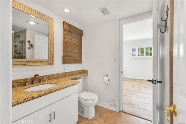 bathroom with wood-type flooring, a tile shower, vanity, and toilet