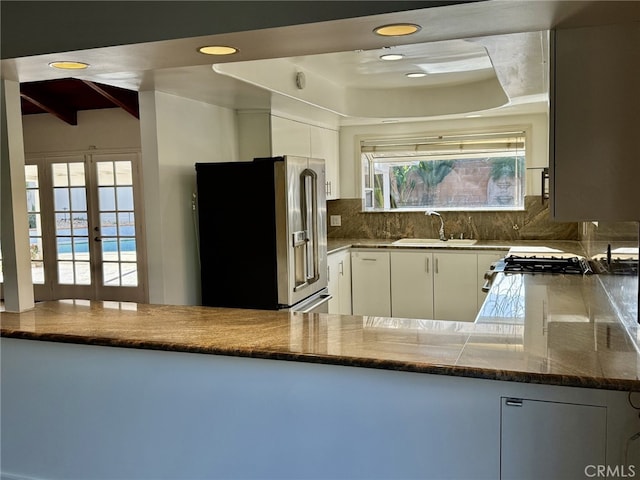 kitchen with high quality fridge, sink, white cabinets, and kitchen peninsula