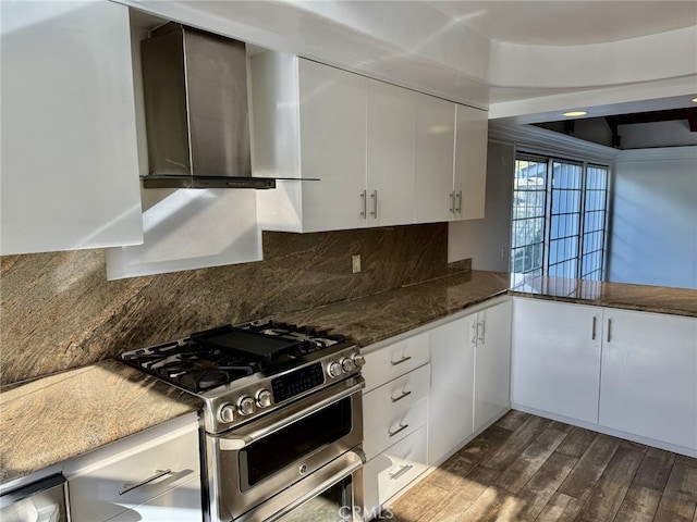 kitchen with dark hardwood / wood-style floors, stainless steel range with gas cooktop, wall chimney exhaust hood, and white cabinets