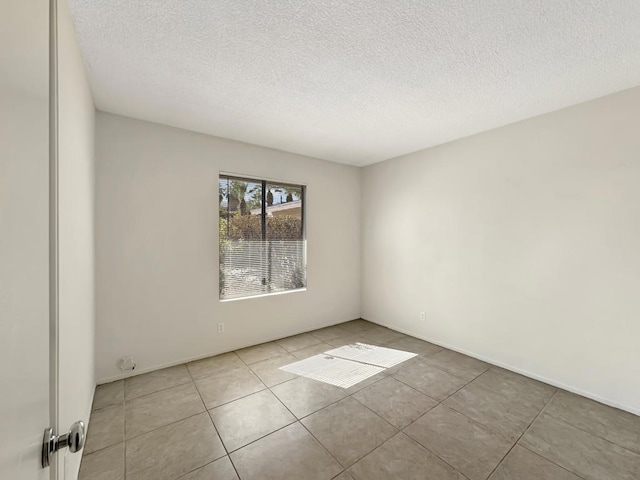 tiled empty room featuring a textured ceiling