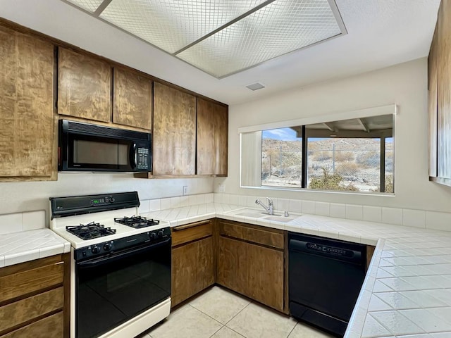 kitchen featuring light tile patterned flooring, sink, tile counters, and black appliances