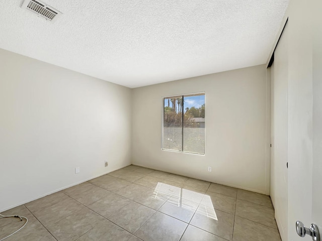 spare room featuring light tile patterned flooring and a textured ceiling