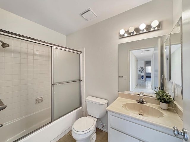 full bathroom with shower / bath combination with glass door, tile patterned flooring, vanity, and toilet