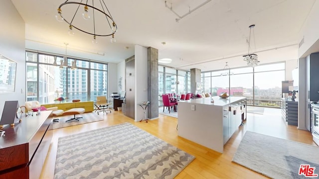 kitchen with white cabinets, light hardwood / wood-style floors, hanging light fixtures, a notable chandelier, and expansive windows