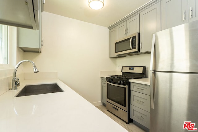 kitchen featuring light tile patterned floors, stainless steel appliances, sink, and gray cabinetry