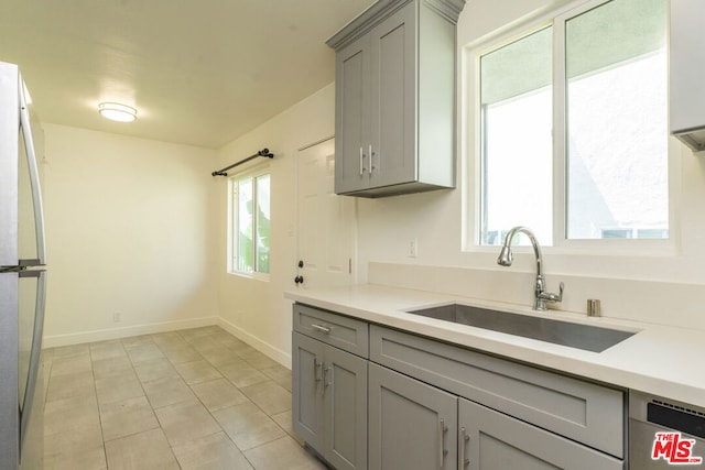 kitchen with gray cabinets, sink, fridge, light tile patterned floors, and stainless steel dishwasher