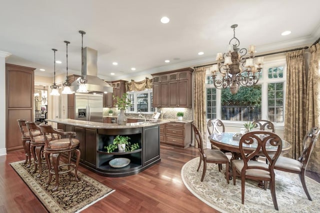 kitchen featuring a wealth of natural light, island range hood, a kitchen island, and stainless steel built in refrigerator