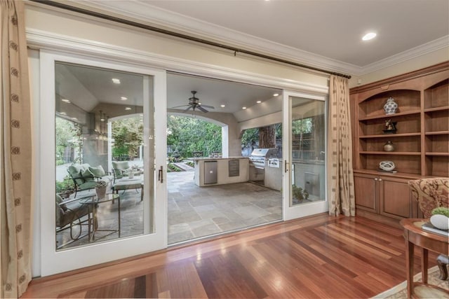 doorway to outside featuring lofted ceiling, hardwood / wood-style floors, crown molding, and ceiling fan