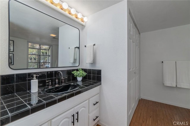 bathroom featuring hardwood / wood-style flooring, backsplash, and vanity