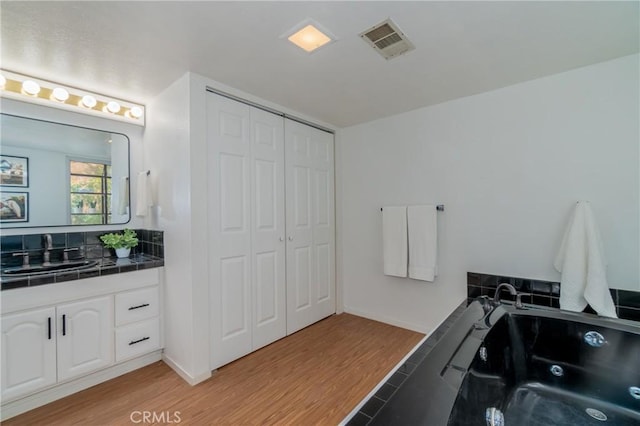 bathroom featuring a bath, hardwood / wood-style floors, and vanity