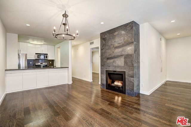 unfurnished living room featuring dark hardwood / wood-style flooring, a fireplace, and a chandelier