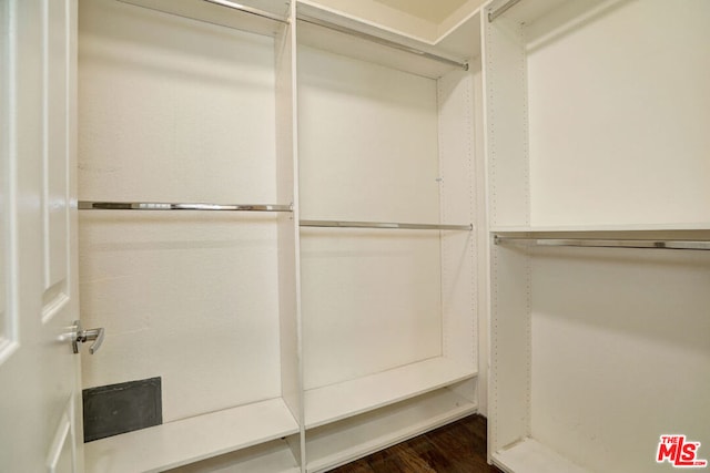 walk in closet with dark wood-type flooring