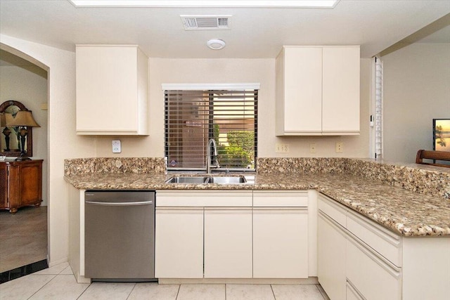 kitchen featuring white cabinetry, stone countertops, light tile patterned floors, stainless steel dishwasher, and sink