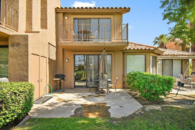 rear view of house featuring a patio and a balcony