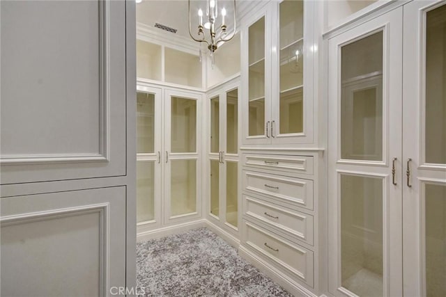 walk in closet featuring a chandelier and light carpet