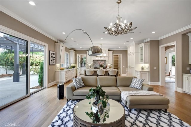 living room with a notable chandelier, light hardwood / wood-style floors, and crown molding