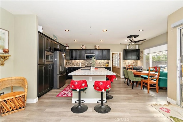 kitchen with ceiling fan, sink, stainless steel appliances, light hardwood / wood-style flooring, and a kitchen island with sink