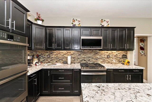 kitchen with decorative backsplash, light stone counters, and appliances with stainless steel finishes