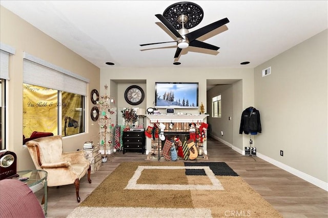 living room with ceiling fan, wood-type flooring, and a brick fireplace