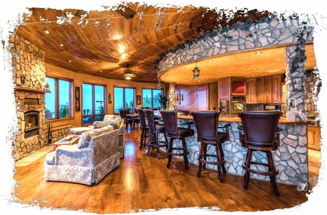 interior space with lofted ceiling, light hardwood / wood-style flooring, oven, wooden ceiling, and a fireplace