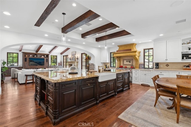 kitchen with dark brown cabinets, a large island, hanging light fixtures, and dark hardwood / wood-style floors