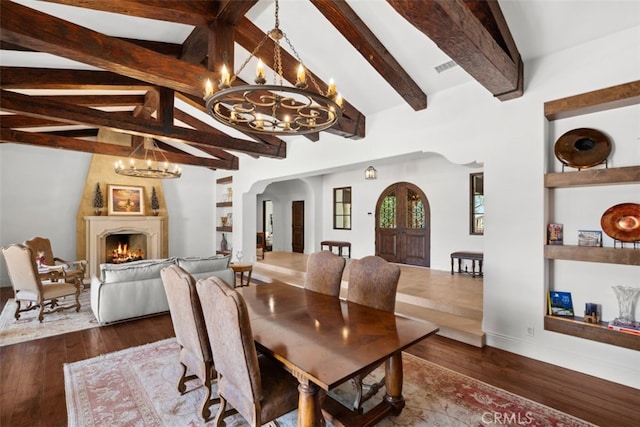 dining room featuring a fireplace, lofted ceiling with beams, dark hardwood / wood-style flooring, and a chandelier