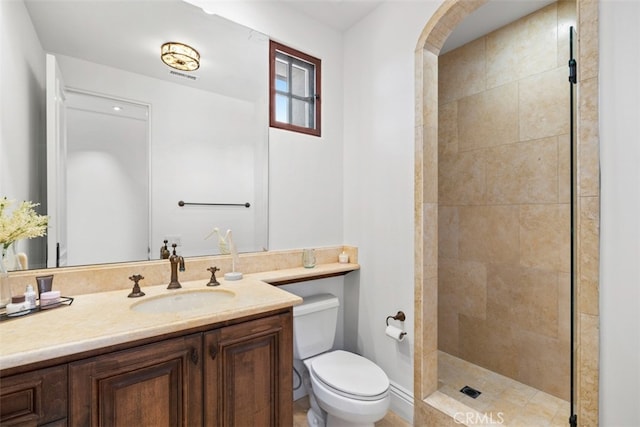 bathroom with vanity, toilet, and tiled shower