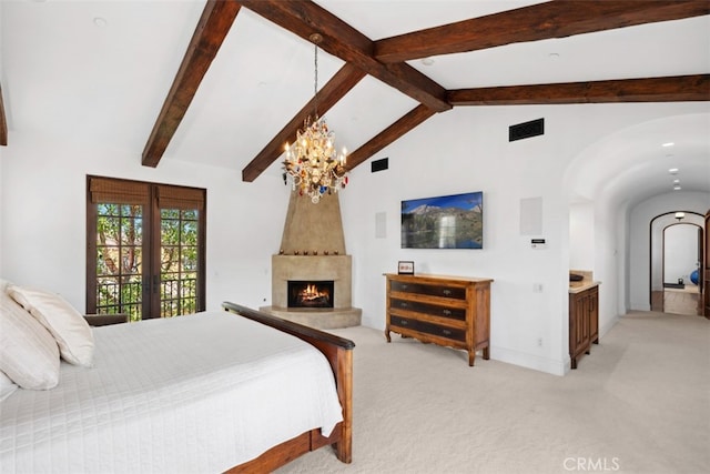 carpeted bedroom with beamed ceiling, connected bathroom, a chandelier, and a large fireplace