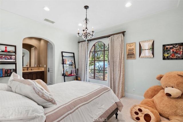 bedroom with light carpet, connected bathroom, and an inviting chandelier