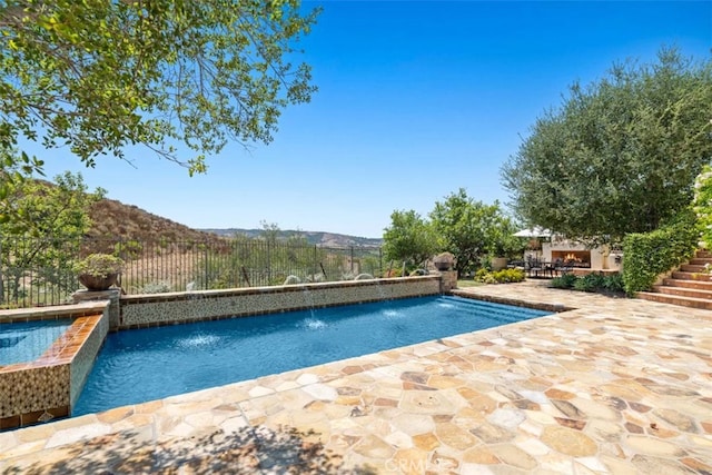 view of swimming pool with pool water feature, a mountain view, and a patio area