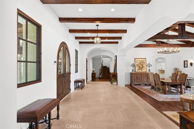 interior space with beamed ceiling, light hardwood / wood-style flooring, a chandelier, and a wealth of natural light