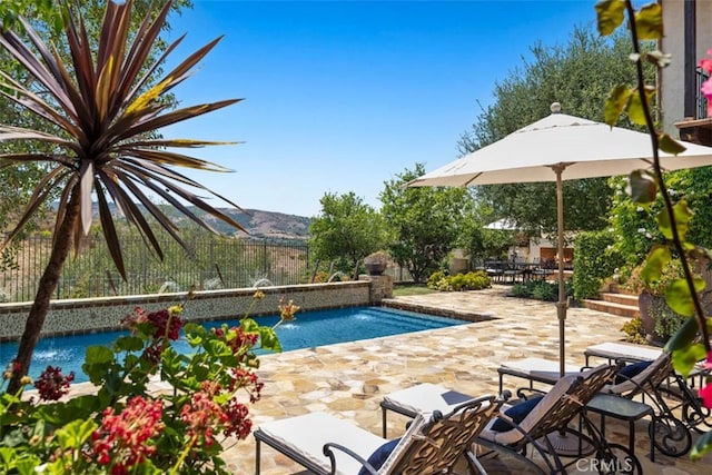 view of swimming pool featuring pool water feature, a mountain view, and a patio area