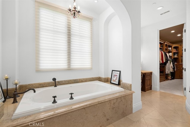 bathroom featuring tiled tub, a chandelier, and tile patterned floors