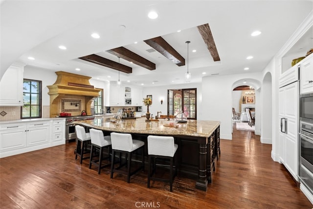 kitchen with high end range, light stone counters, dark hardwood / wood-style floors, and a spacious island